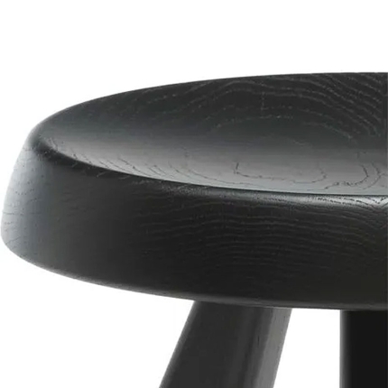 Gros plan sur l'assise ronde en chêne teinté noir du tabouret Berger de Charlotte Perriand