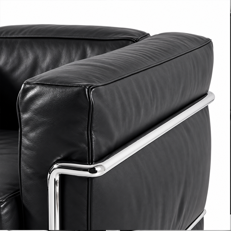 Gros plan sur les coussins en cuir noir et la structure tubulaire chromée du canapé LC2 Cassina