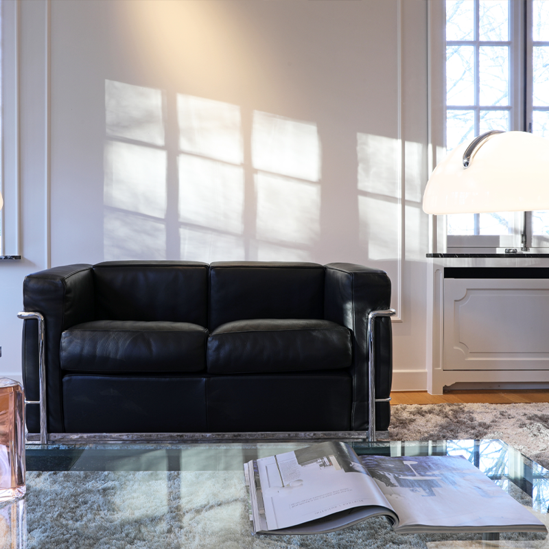 Canapé LC2 Cassina en cuir noir installé devant une fenêtre dans un salon contemporain lumineux