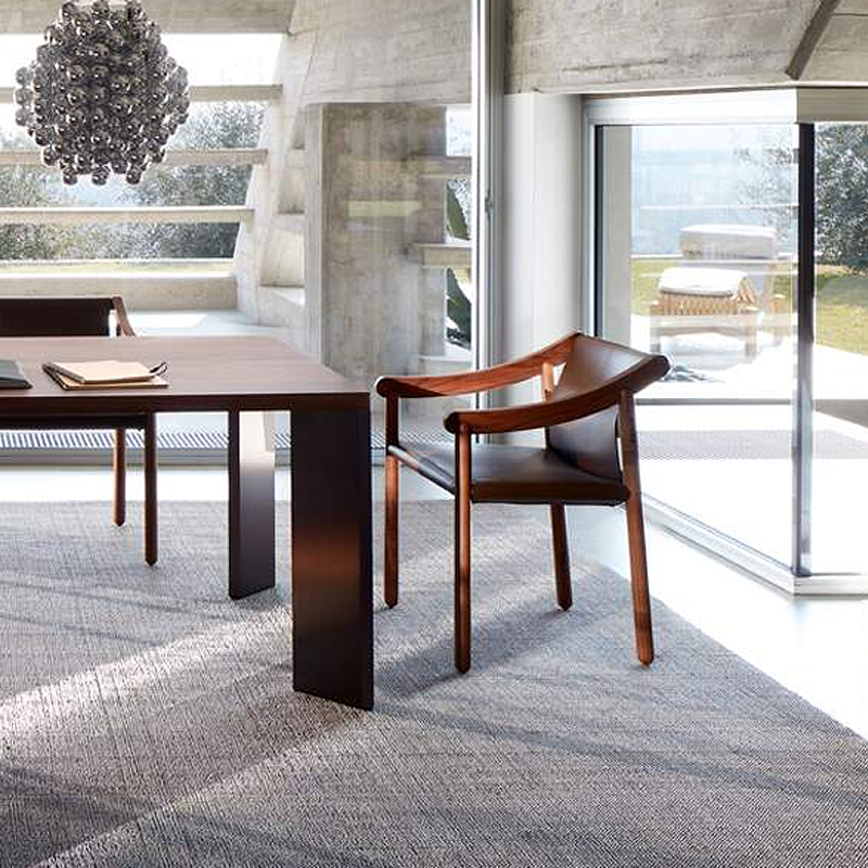 Chaise 905 Cassina en noyer Canaletto et cuir noir près d'une table design devant une baie vitrée
