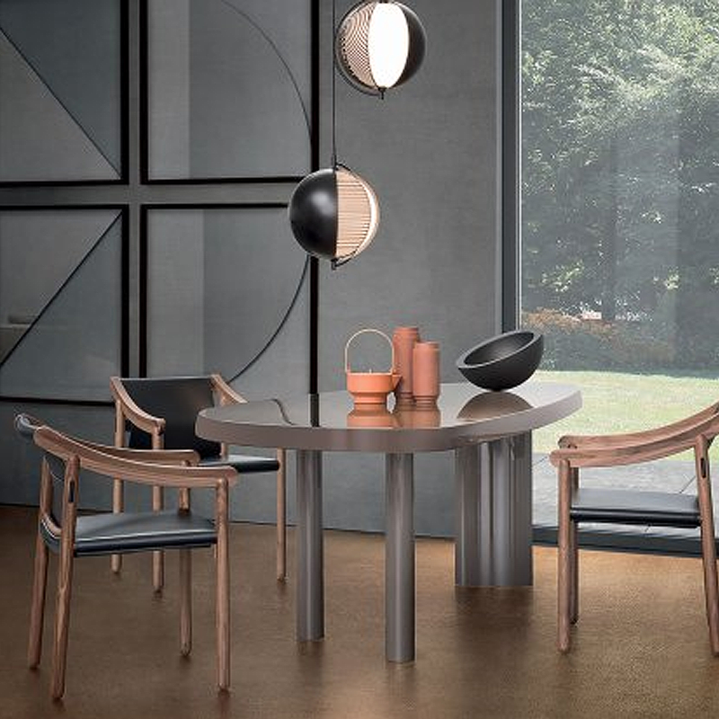 Chaises 905 en noyer et cuir noir de Vico Magistretti autour d'une table ronde dans une salle à manger contemporaine