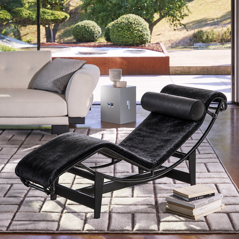 Chaise longue LC4 Cassina en peau noire devant un canapé clair dans un salon contemporain ouvert sur le jardin