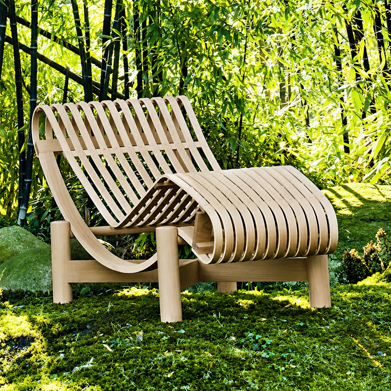 Chaise longue Tokyo 522 Cassina en bois naturel installée sur une pelouse près d'un arbre