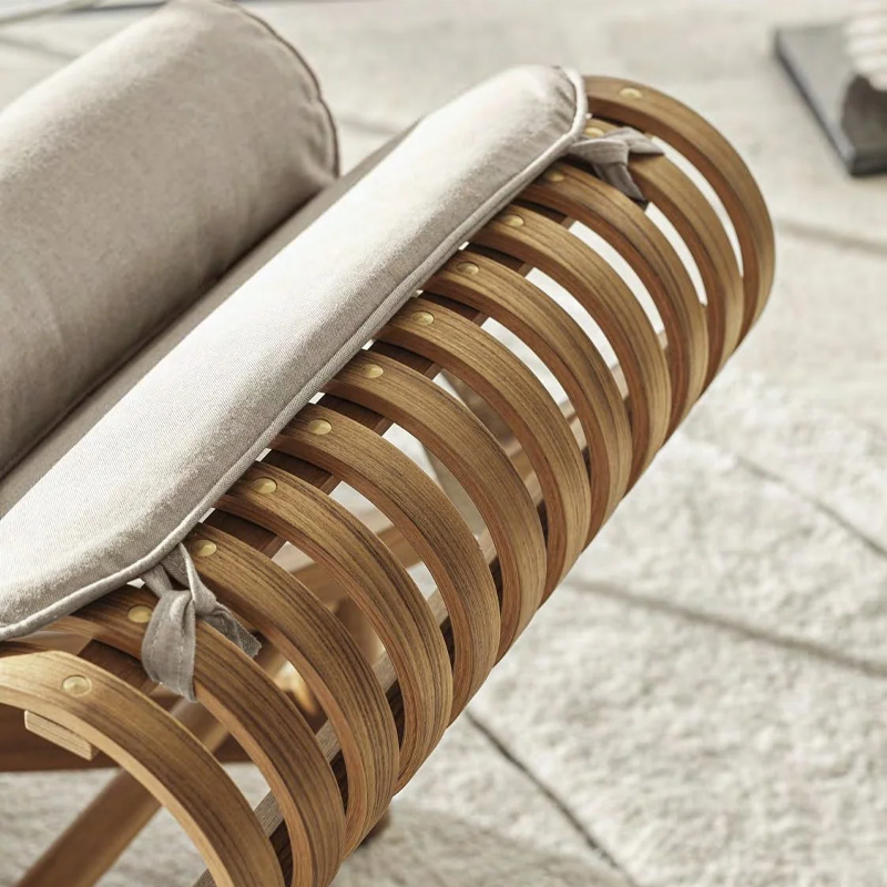 Gros plan sur le dossier à lattes courbées et la structure en bois naturel de la chaise longue Tokyo Cassina