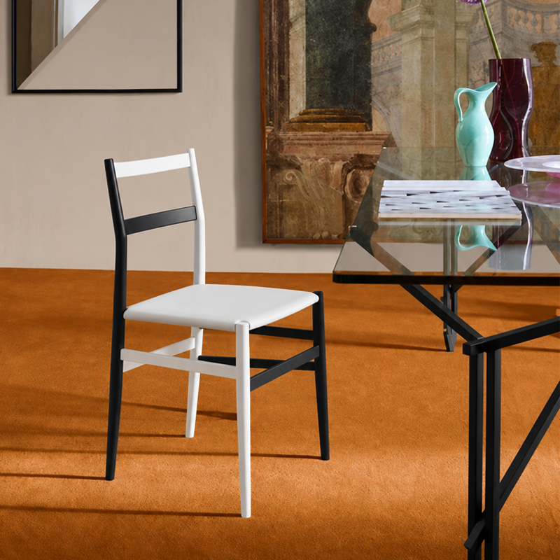 Chaise Superleggera bicolore de Gio Ponti près d'une table en verre dans une salle à manger élégante