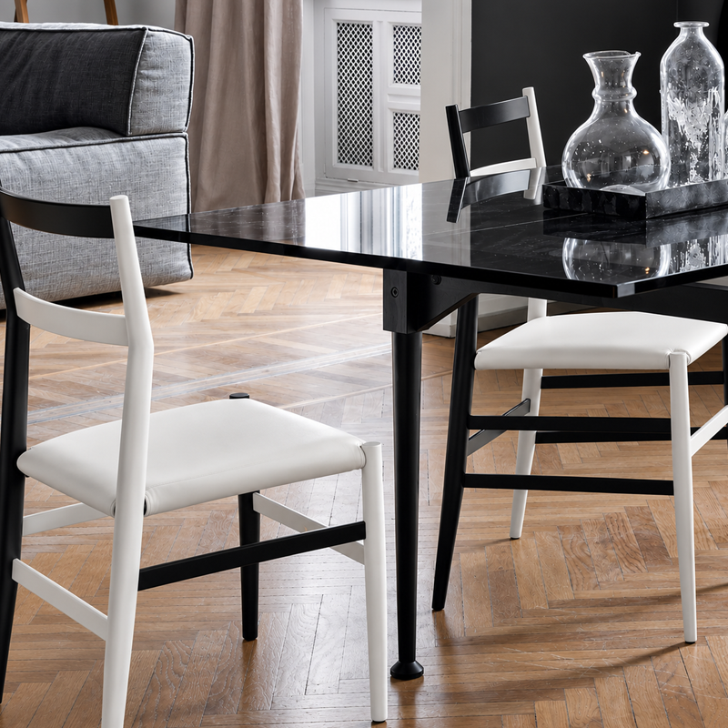 Chaises Superleggera Cassina bicolores avec assises blanches autour d'une table noire dans un intérieur contemporain
