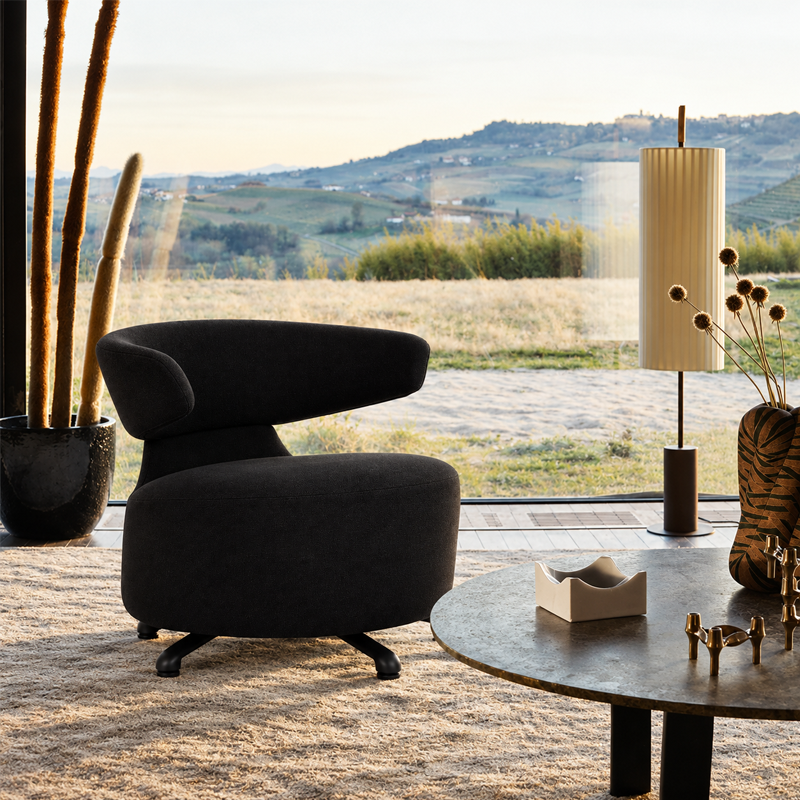 Fauteuil Biki noir de Toshiyuki Kita près d'une table basse dans un salon lumineux ouvert sur un paysage naturel
