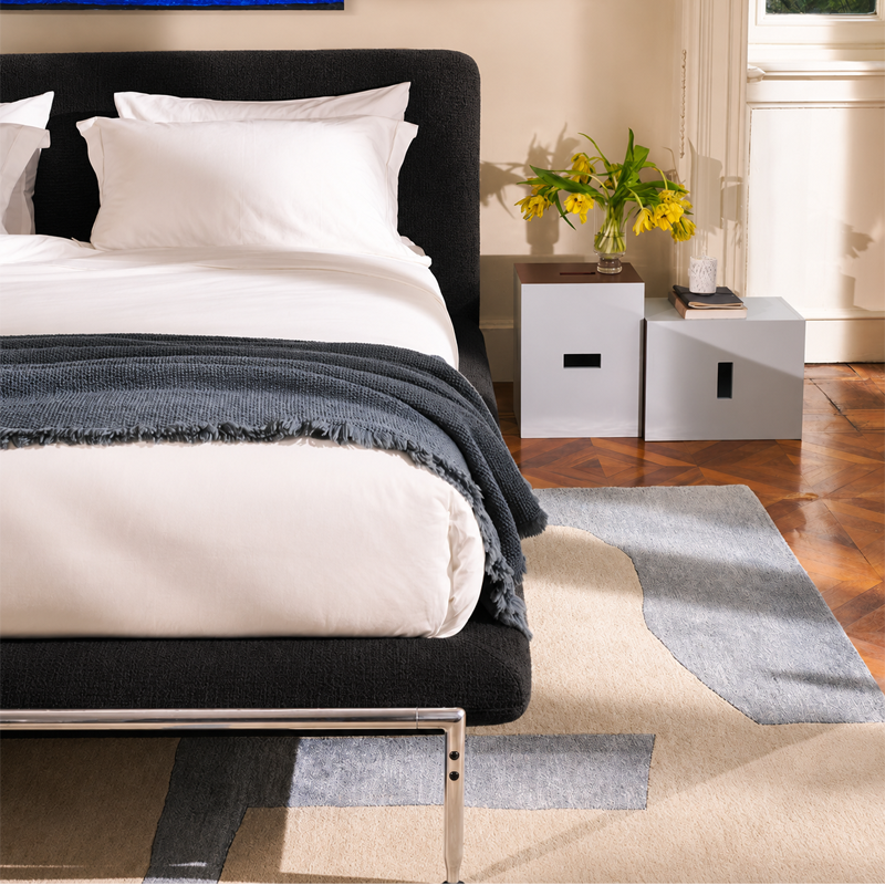 Lit Esosoft noir de Antonio Citterio dans une chambre élégante avec linge de lit blanc et mobilier contemporain