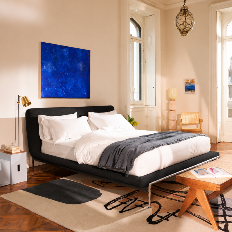 Lit Esosoft Cassina en tissu noir dans une chambre lumineuse avec tableau bleu et parquet en bois