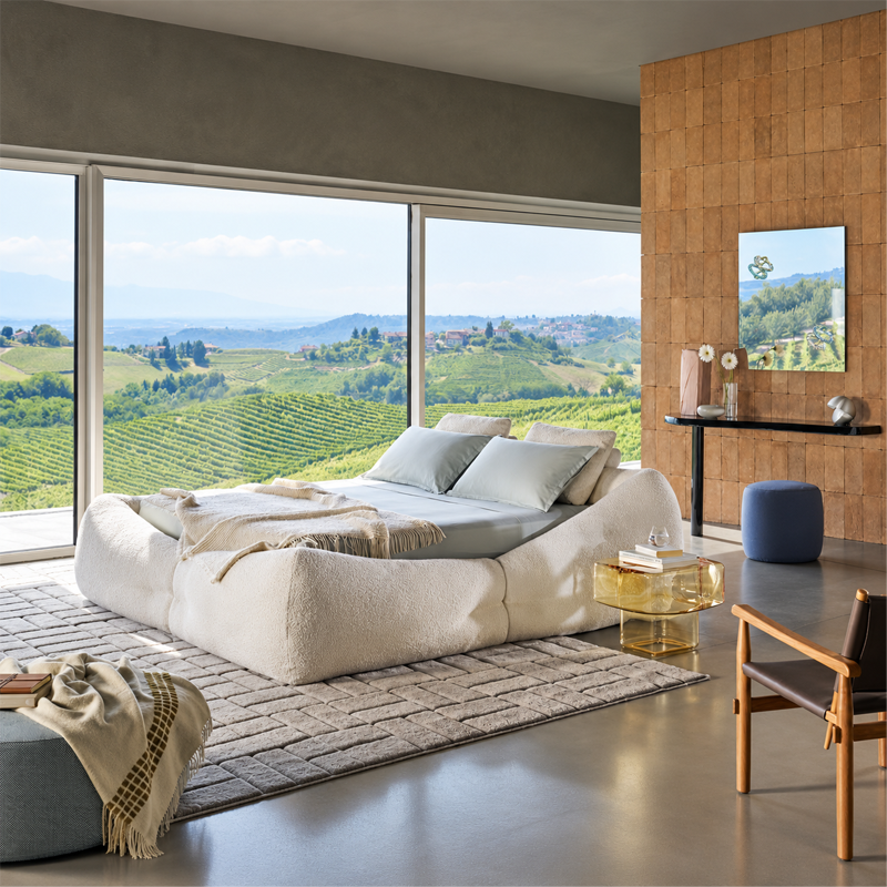 Lit Mon-Nid Cassina en tissu écru dans une chambre contemporaine ouverte sur un paysage verdoyant