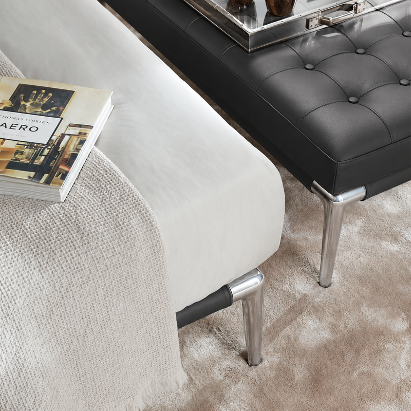 Vue rapprochée du capitonnage noir et des pieds en aluminium poli du lit Volage Cassina