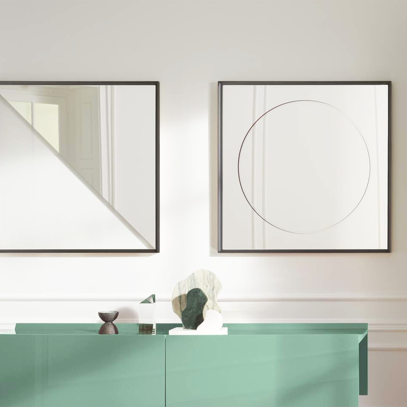 Miroir Eternal Sun de Ron Gilad présenté avec un second miroir géométrique au-dessus d'un meuble vert d'eau