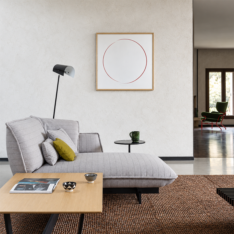 Miroir Eternal Sun Cassina avec cercle graphique accroché au-dessus d'un canapé gris dans un salon contemporain