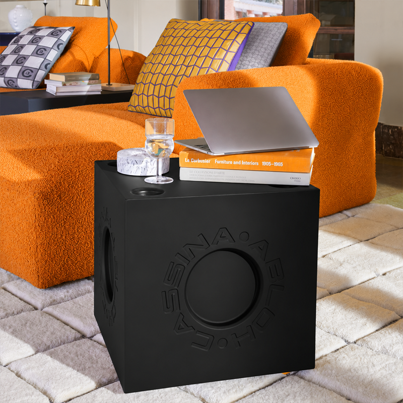 Module Modular Imagination Cassina noir utilisé comme table d'appoint avec ordinateur portable près d'un canapé orange