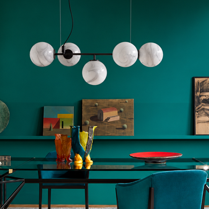 Suspension Starburst Cassina en verre marbré blanc au-dessus d'une table dans une salle à manger aux murs vert émeraude