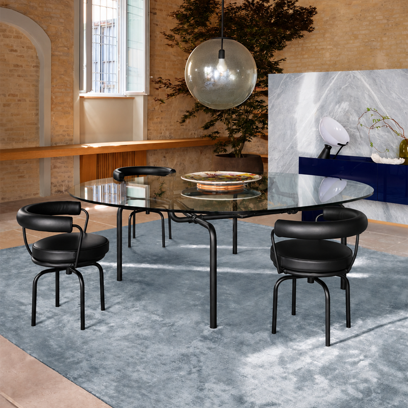 Table Edison noire Cassina avec plateau rond en verre dans une salle à manger contemporaine avec chaises design