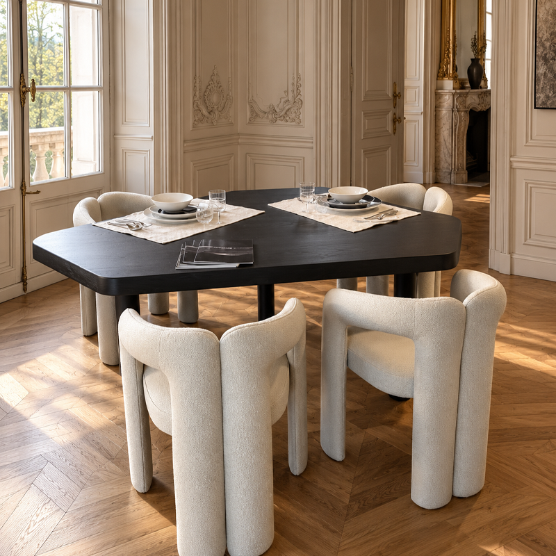 Table Montparnasse noire de Charlotte Perriand entourée de fauteuils blancs dans une salle à manger élégante avec parquet