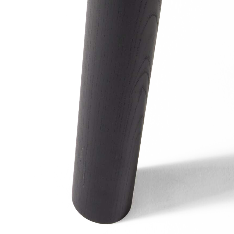Gros plan sur un pied cylindrique en frêne massif teinté noir de la table Montparnasse Cassina