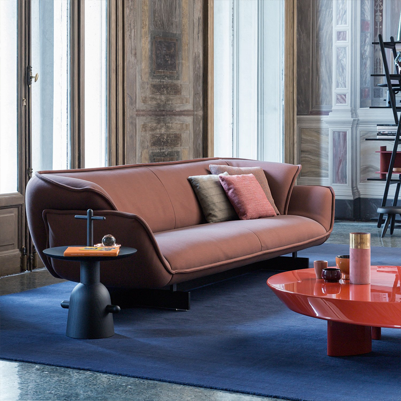 Table Réaction Poétique noire de Jaime Hayon devant un canapé en cuir cognac sur un tapis bleu