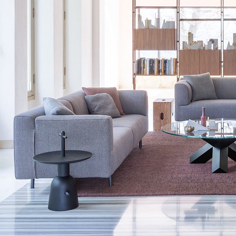 Table Réaction Poétique 081 06 noire dans un salon lumineux avec canapé gris bleuté et mobilier contemporain