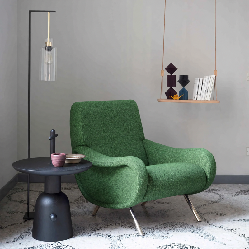 Table d'appoint Réaction Poétique noire de Cassina à côté d'un fauteuil vert dans un salon contemporain