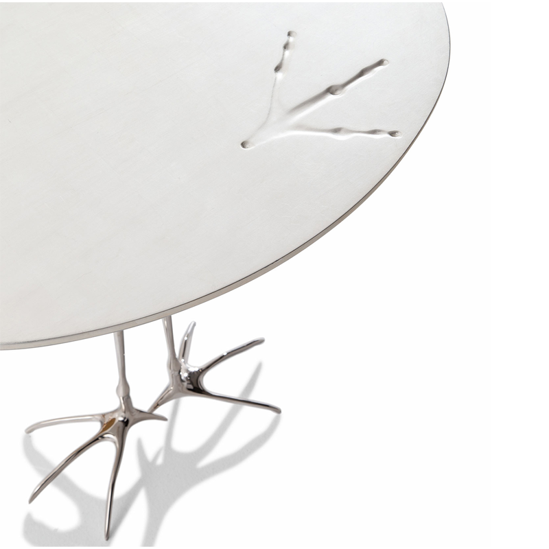 Gros plan sur les empreintes d'oiseau du plateau en feuille d'or blanc de la table Traccia Cassina