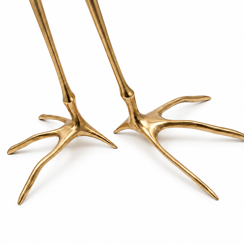 Gros plan sur les deux pieds en bronze doré en forme de pattes d'oiseau de la table Traccia Cassina