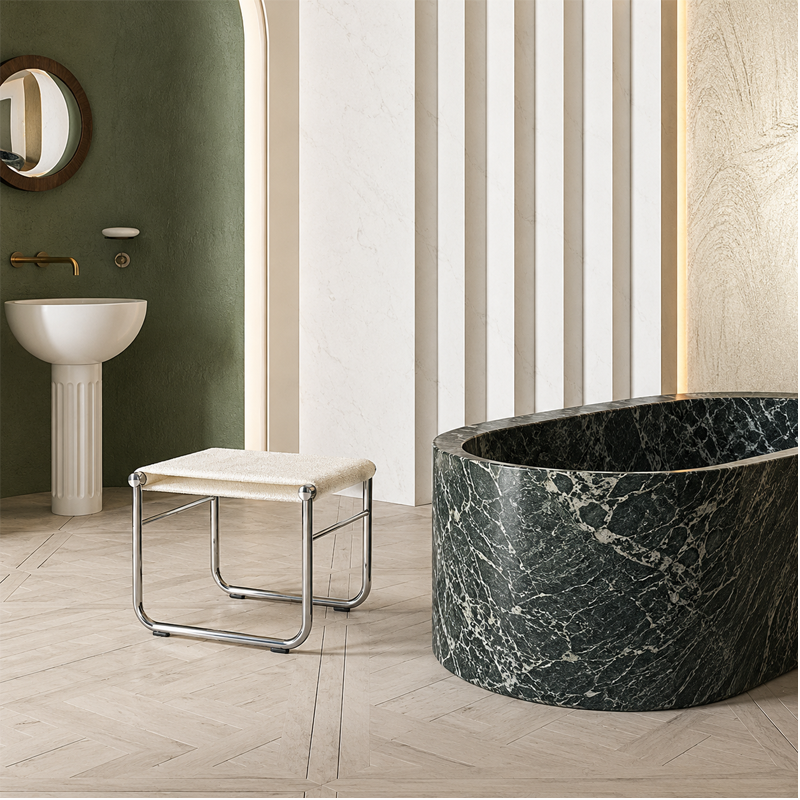 Tabouret de salle de bains 009 Cassina avec assise blanche près d'une baignoire habillée de marbre vert